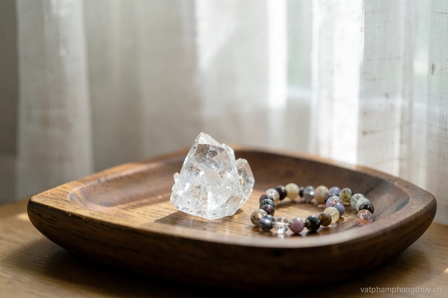 A small clear quartz cluster on a wooden bedside tray with a stone bead bracelet resting beside it, early morning light through linen curtains