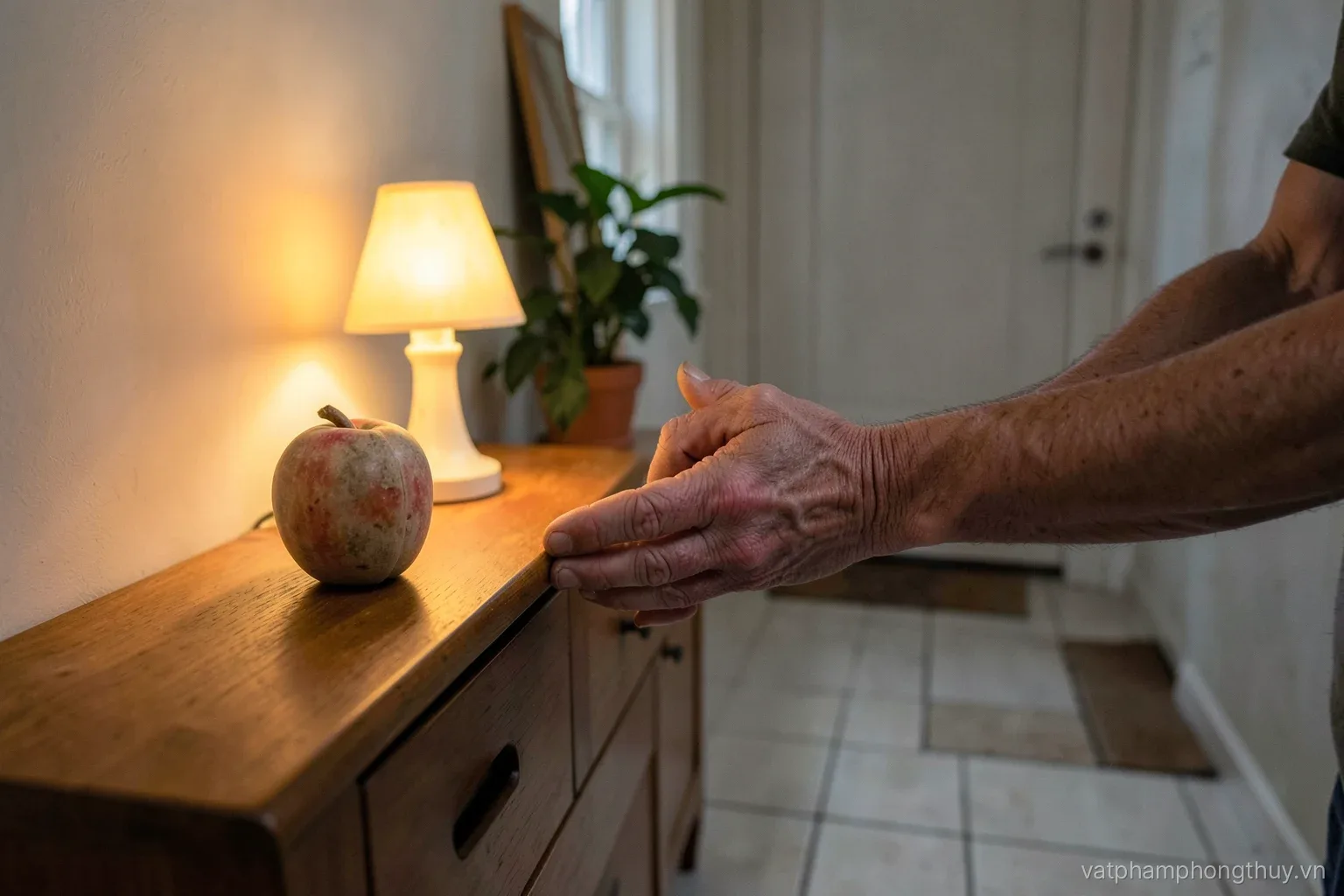 Wrinkled hands placing a small soapstone longevity peach on a low bedside cabinet, warm night lamp glowing, clear tiled floor path to the door